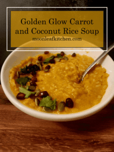 Creamy Coconut Carrot & Jasmine Rice Soup Overhead shot of a bowl of orange carrot and coconut soup with white jasmine rice, topped with green cilantro, green pepitas, and red pomegranate seeds