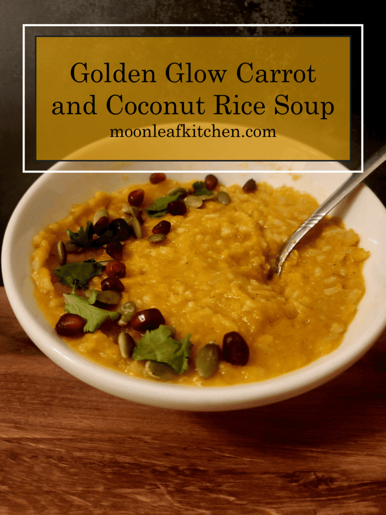 Creamy Coconut Carrot & Jasmine Rice Soup Overhead shot of a bowl of orange carrot and coconut soup with white jasmine rice, topped with green cilantro, green pepitas, and red pomegranate seeds