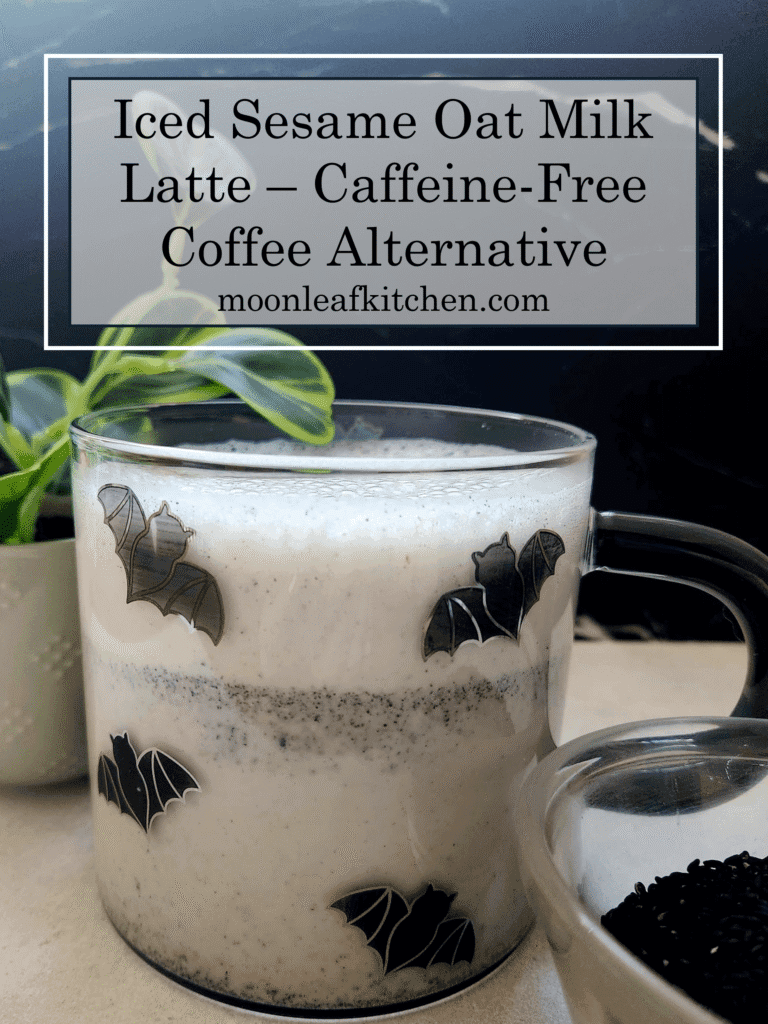 Iced Black Sesame Latte - A Caffeine-Free Coffee Alternative A side view of a gray sesame latte against a black and white background with a bowl of black sesame seeds beside it.